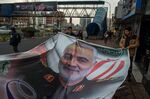 People prepare to hang a poster of Qassem Soleimani, an Iranian commander, following a U.S. airstrike in Iraq, in Tehran, Iran, on Sunday, Jan. 5, 2020.