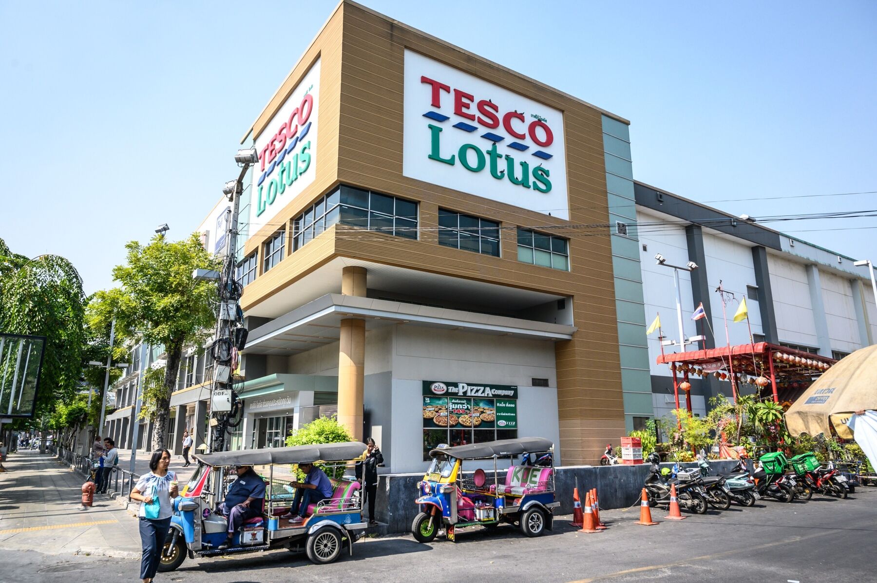 Tuk Tuk drivers wait for customers outside a Tesco-Lotus supermarket in Bangkok