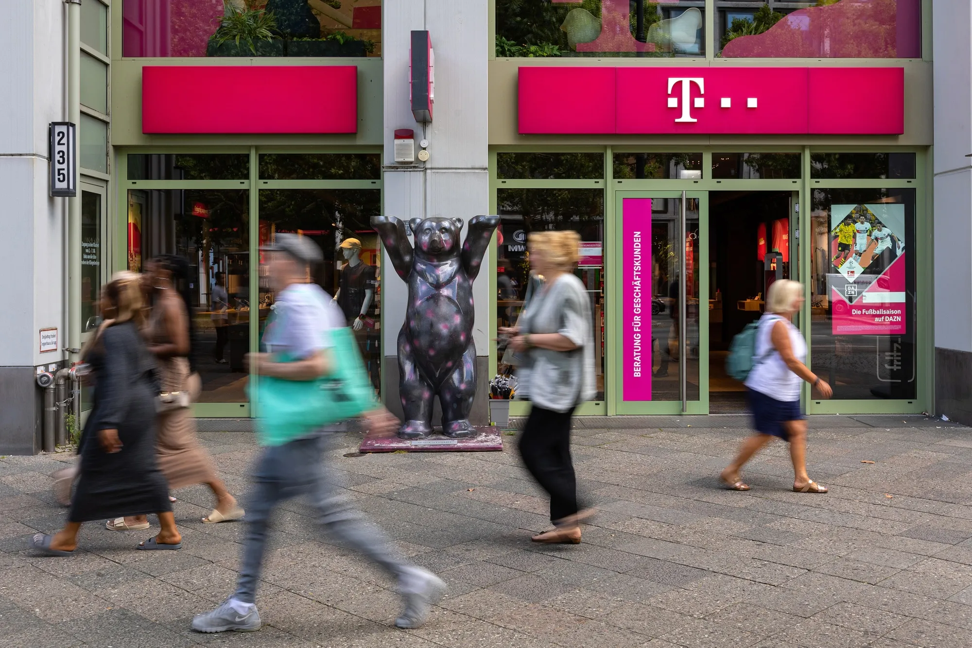 Pedestrians pass a Deutsche Telekom AG store in Berlin.
