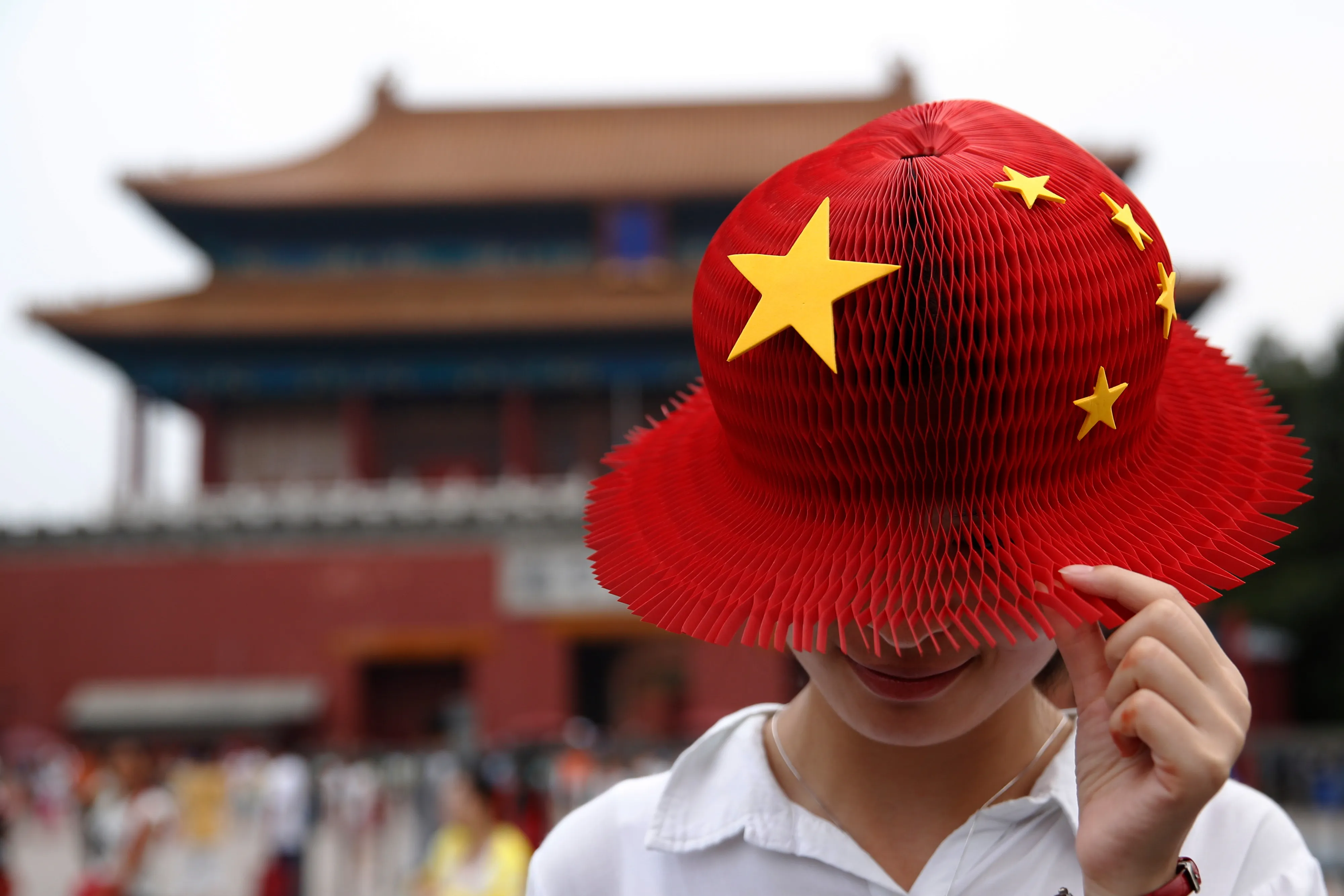 A women wears a bright red hat, covered with yellow stars in the style of the People's Republic of China's national flag, also known as the Five-star Red flag as she visits the Forbidden City in Beijing, China, on Thursday, July 28, 2016. As China's travel market takes off, all eyes should be on the country's roughly 400 million millennials, who will drive spending on airfare, hotels, theme parks, casinos and cruises.