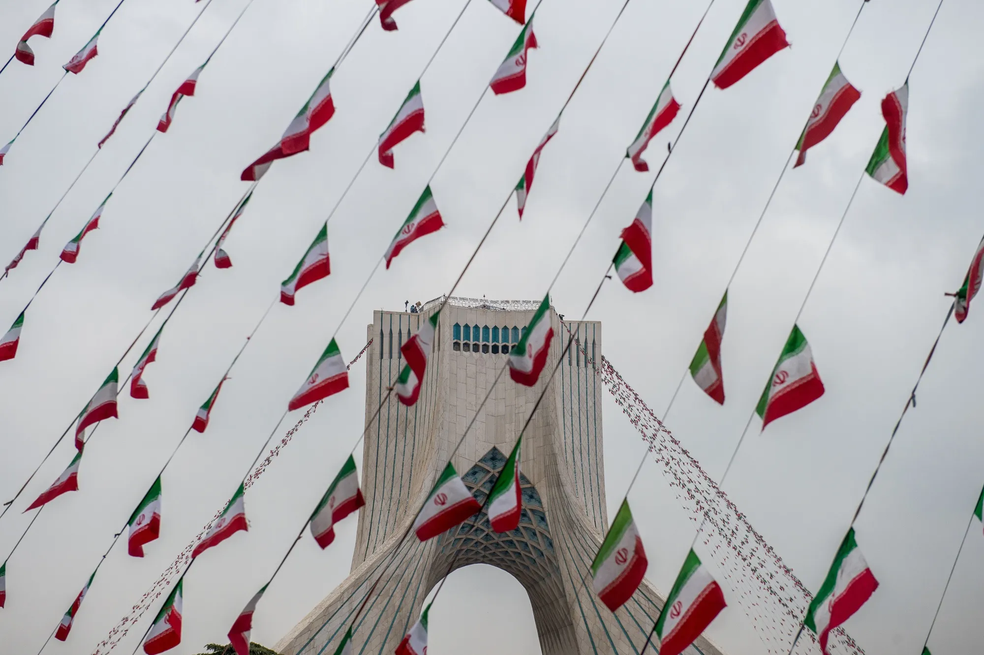Iranian national flag bunting hangs in front of the Azadi Tower&nbsp;in Tehran, Iran.