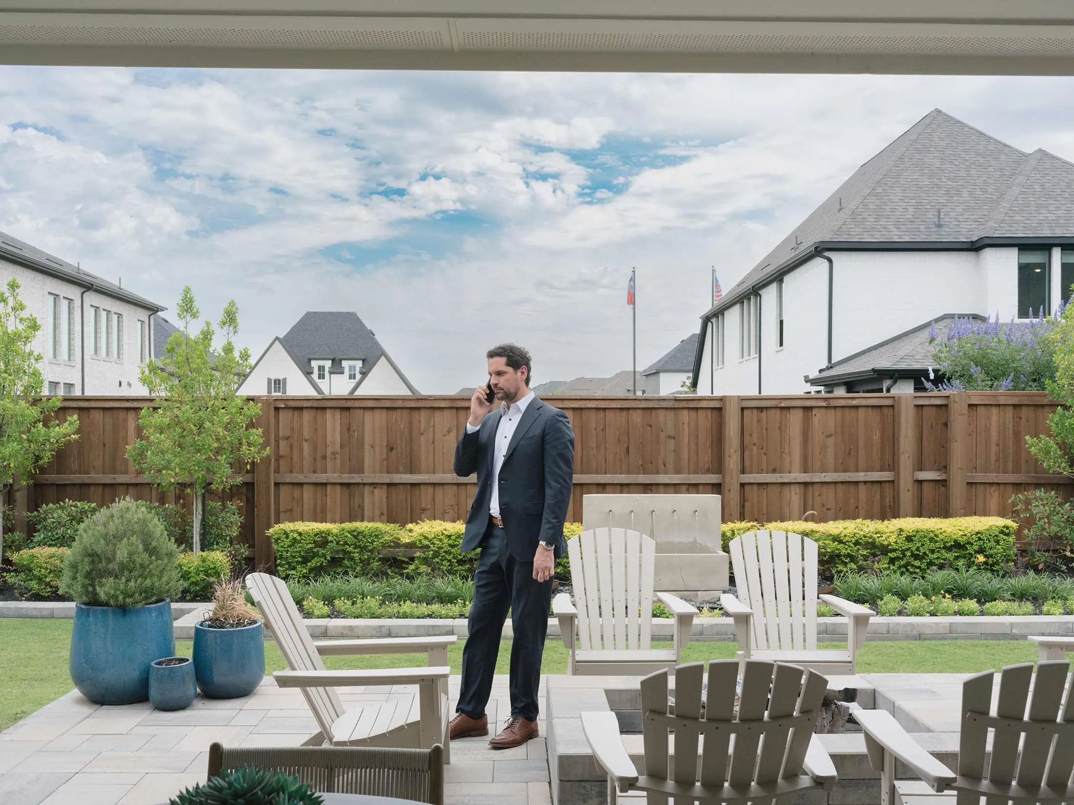 Zach Schneider talks on the phone in the backyard of a model home in Celina, Texas.