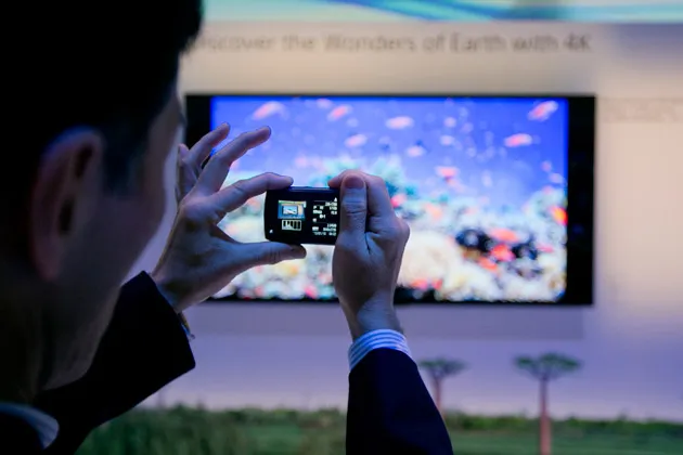 An attendee takes a photograph of a Sony 65-inch 4K LED television at CES 2013 in Las Vegas