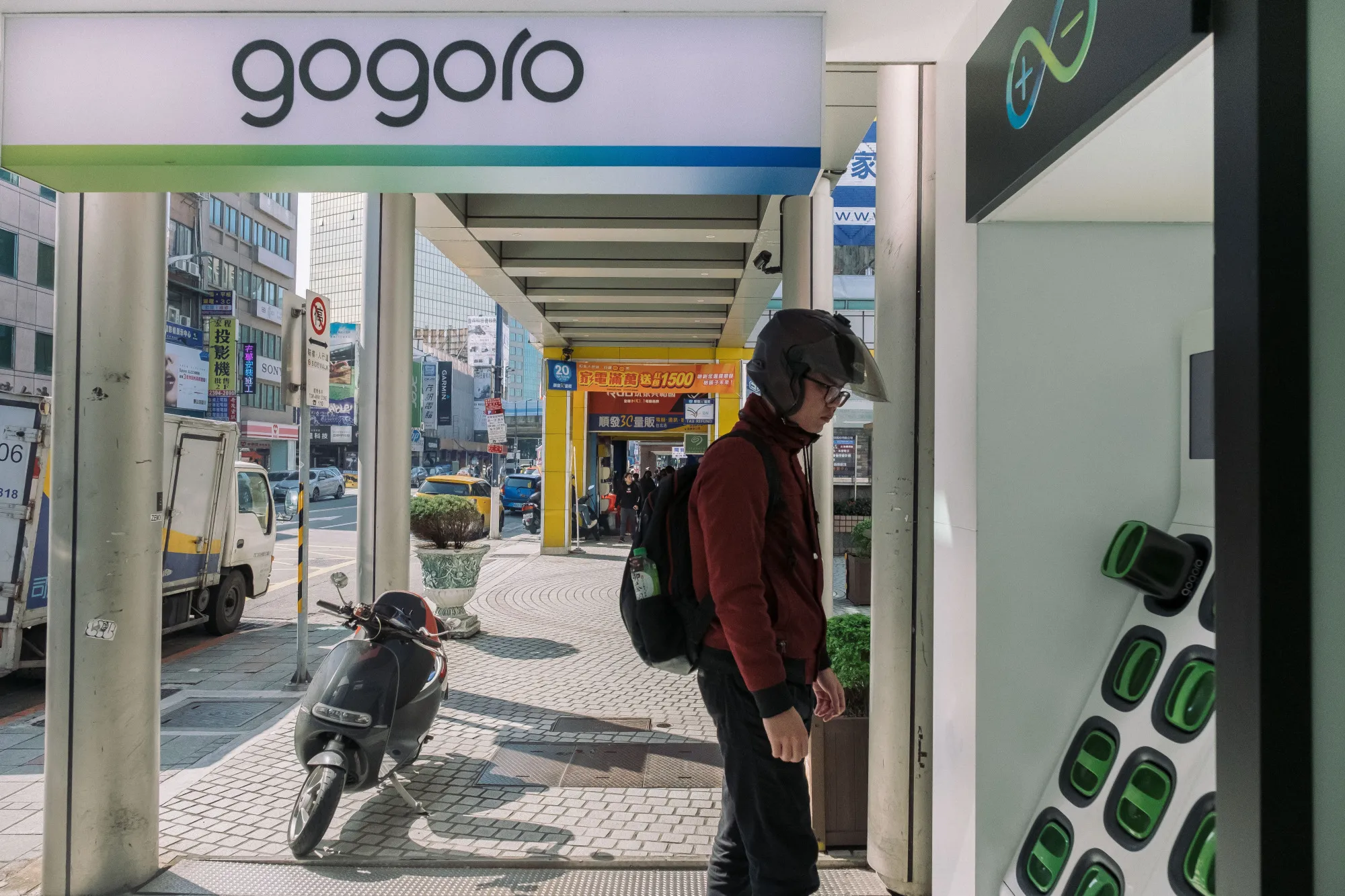 A man stands next to a Gogoro Inc. battery charging station outside one of the company's stores in Taipei.