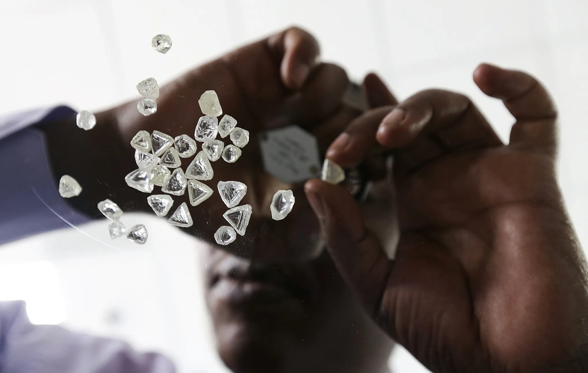 An employee inspects uncut diamonds at a unit of De Beers, in Gaborone, Botswana.