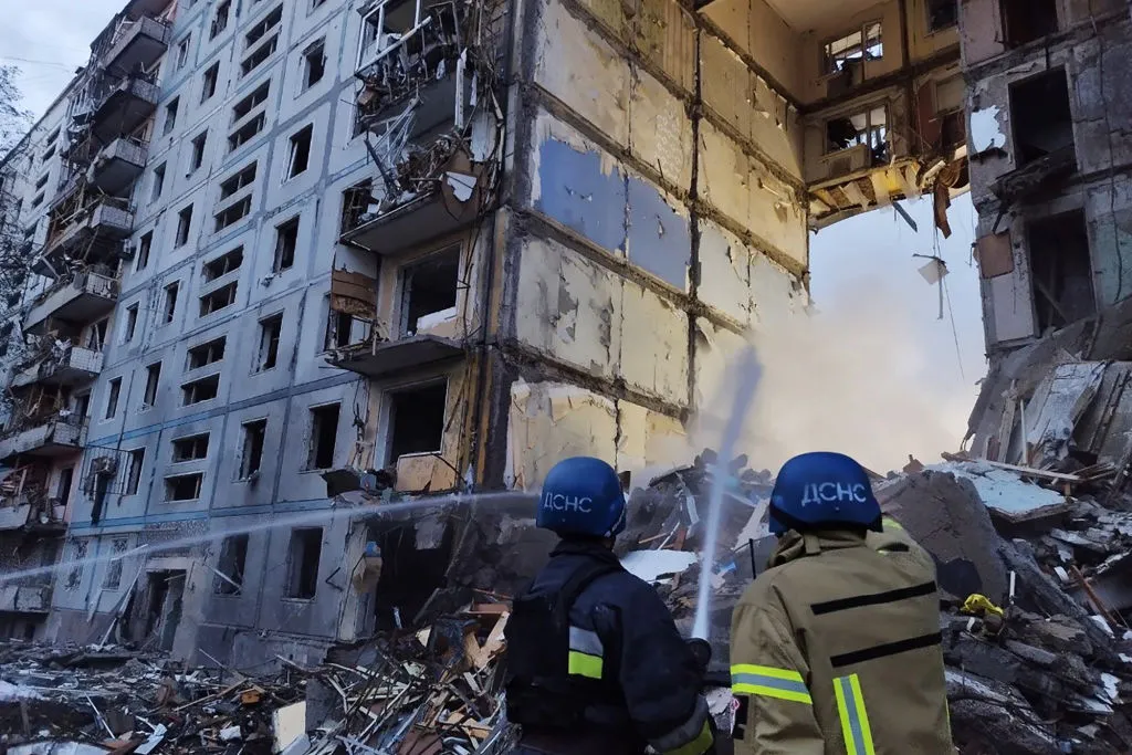 Rescuers use a hose to extinguish a fire in a residential building in Zaporizhzhia, Ukraine on October 9.&nbsp;