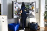 A Walmart associate stocking a refrigerator with InHome delivery.