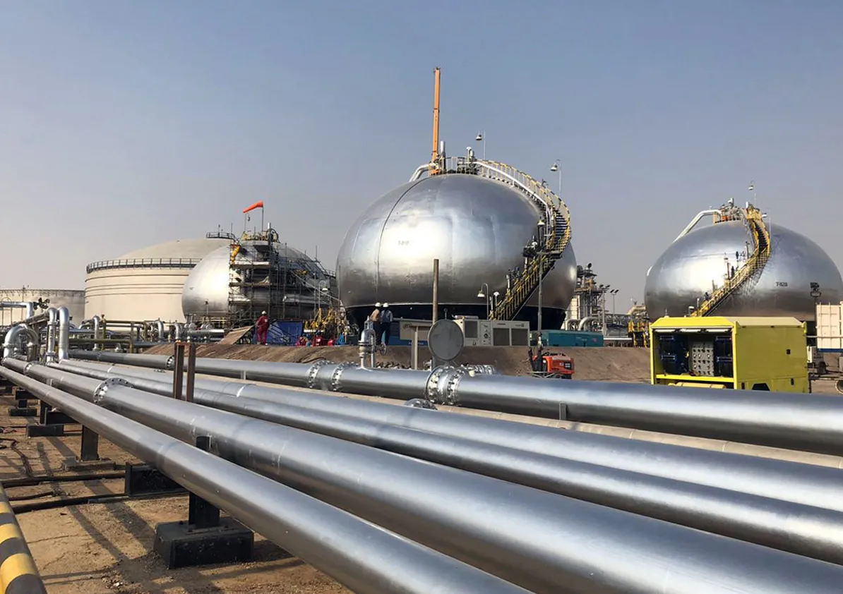 Three-phase spheroids stand behind pipelines at Saudi Aramco's crude oil processing facility, in Abqaiq, Saudi Arabia.