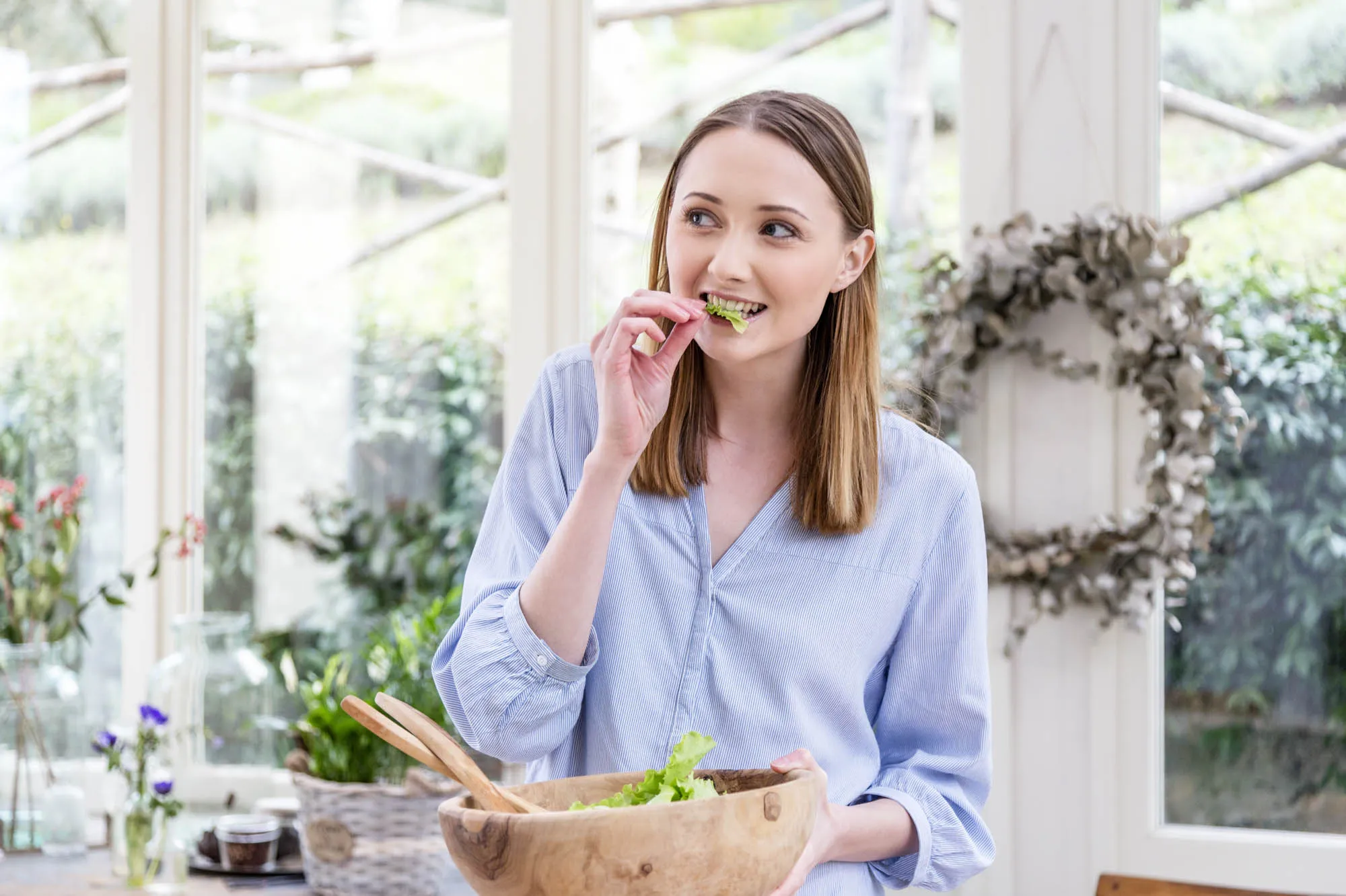 Woman eating salad leaves looking away