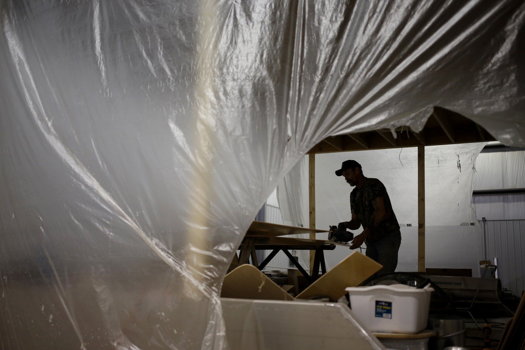 A worker cuts wood paneling with a circular saw while working on a custom houseboat at the Majestic Yachts Inc. manufacturing facility in Columbia, Kentucky.