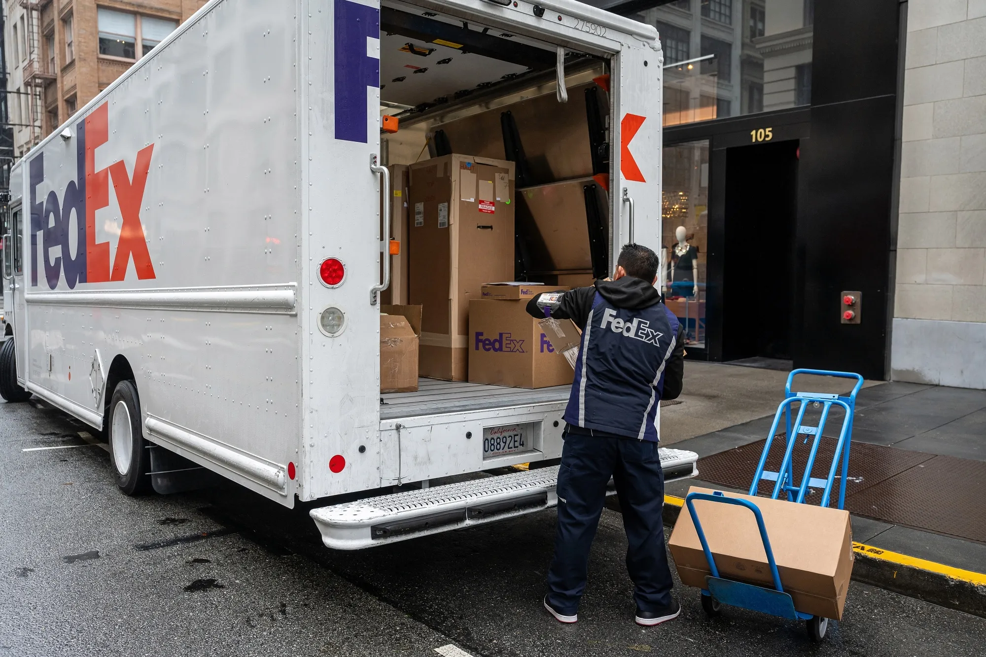 A worker unloads packages from a FedEx truck in San Francisco, California, US.
