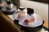 Plates of sushi covered with domes move along a conveyor belt.