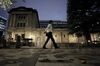 A pedestrian walks past the Bank of Japan (BOJ) headquarters at dusk in Tokyo, Japan, on Monday, Sept. 14, 2020. 