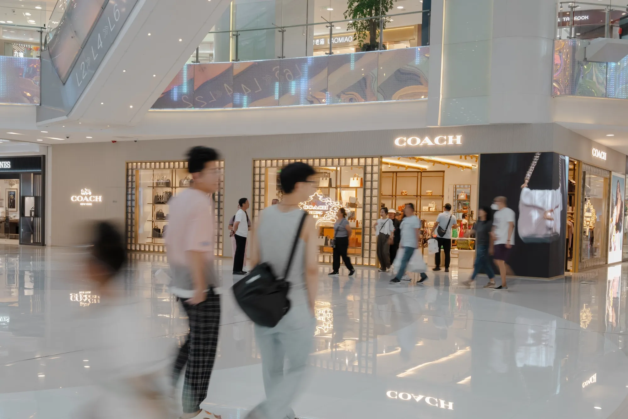 Shoppers walk past a Coach store in the Wangfujing shopping area in Beijing.