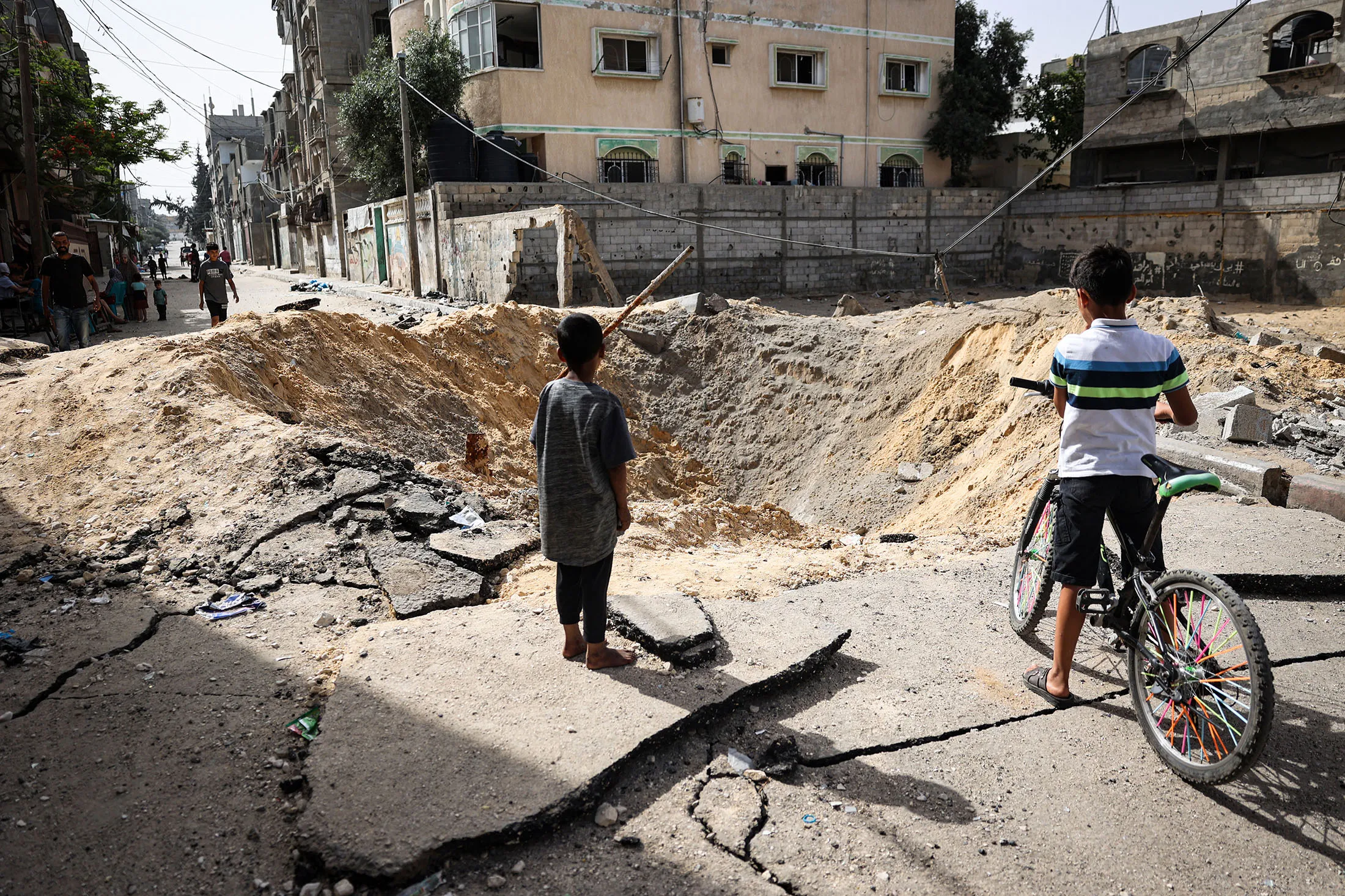 Children stand near a crater caused by a bombardment in a street in Rafah in the southern Gaza Strip on May 18.
