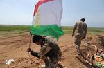 A peshmerga fighter plants a Kurdish flag near of Kirkuk, northern Iraq.

