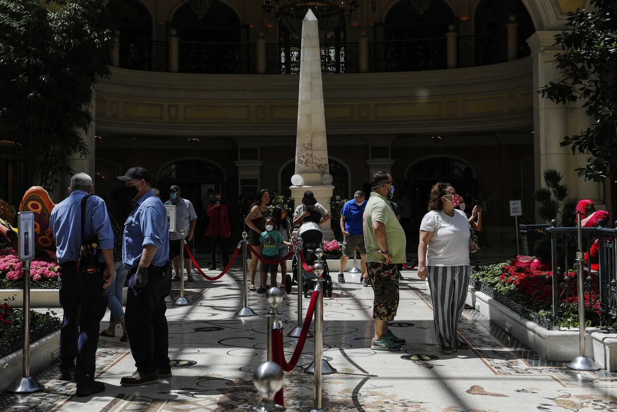 People wearing protective masks walk through the Bellagio Hotel and Casino.