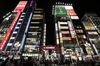 Commercial buildings stand illuminated with neon signs while pedestrians walk through a street at night in the Shinjuku district of Tokyo, Japan, on Friday, May 13, 2016. Japan's first quarter gross domestic product (GDP) will be announced on Wednesday, May 18, 2016.