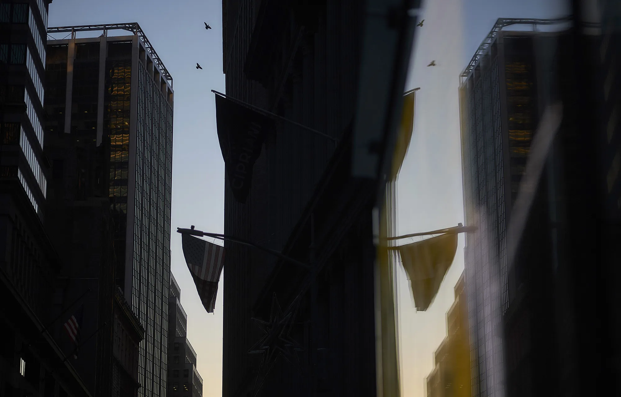 An American flag is reflected in the window of a building near the New York Stock Exchange.