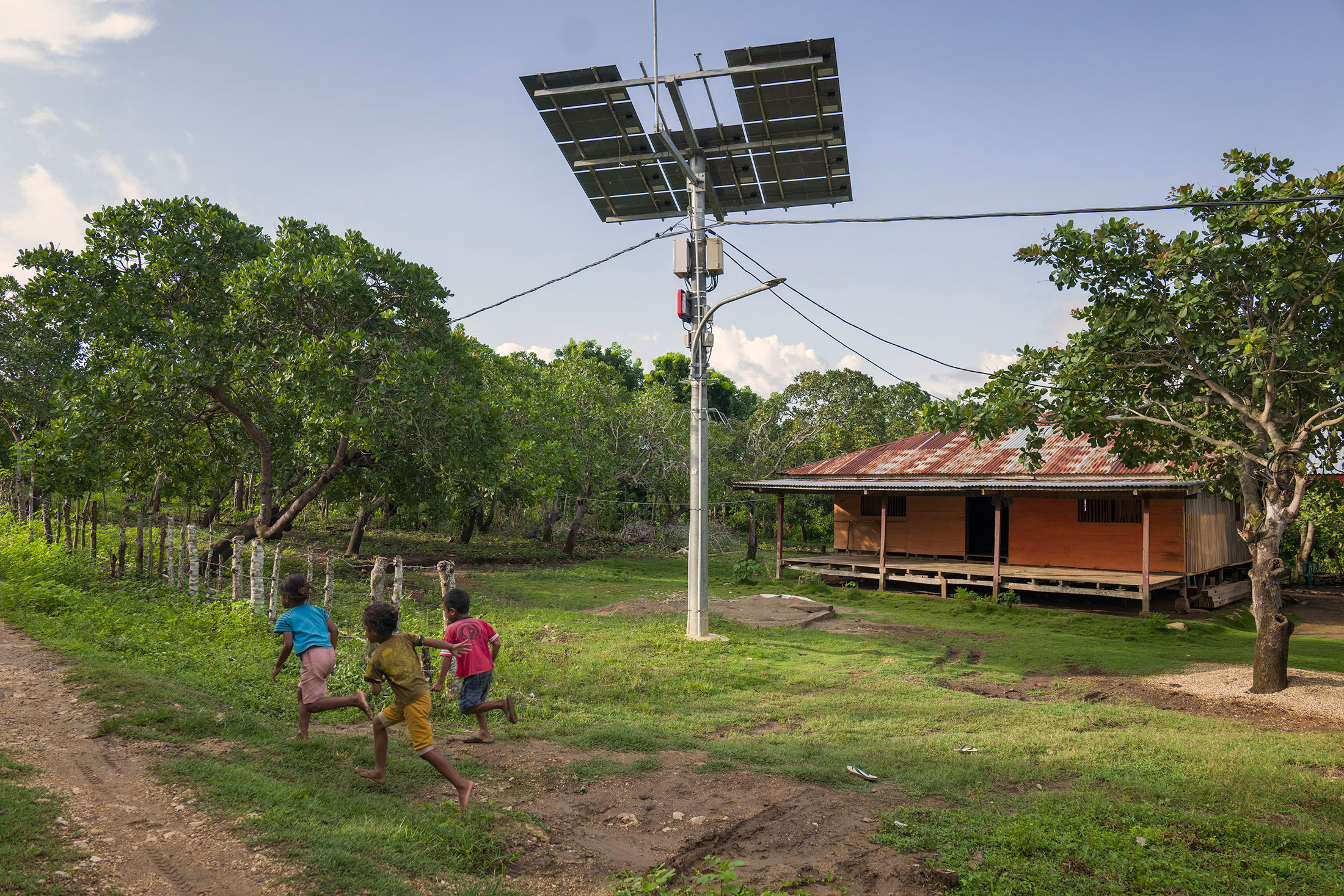 Children run pass a solar panel that was damaged by a recent hurricane