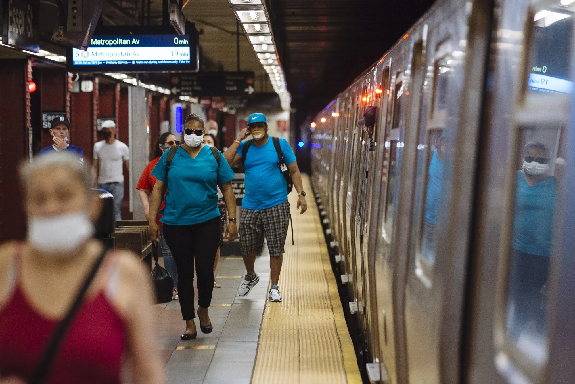People wearing protective masks walk through a subway station in New York.