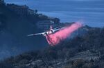 A plane drops retardant on a wildfire near homes Thursday, Feb. 10, 2022, in Laguna Beach, Calif. U.S. officials are testing a new wildfire retardant after two decades of buying millions of gallons annually from one supplier, but watchdogs say the expensive strategy is overly fixated on aerial attacks at the expense of hiring more fire-line digging ground crews.  (AP Photo/Ringo H.W. Chiu, File)