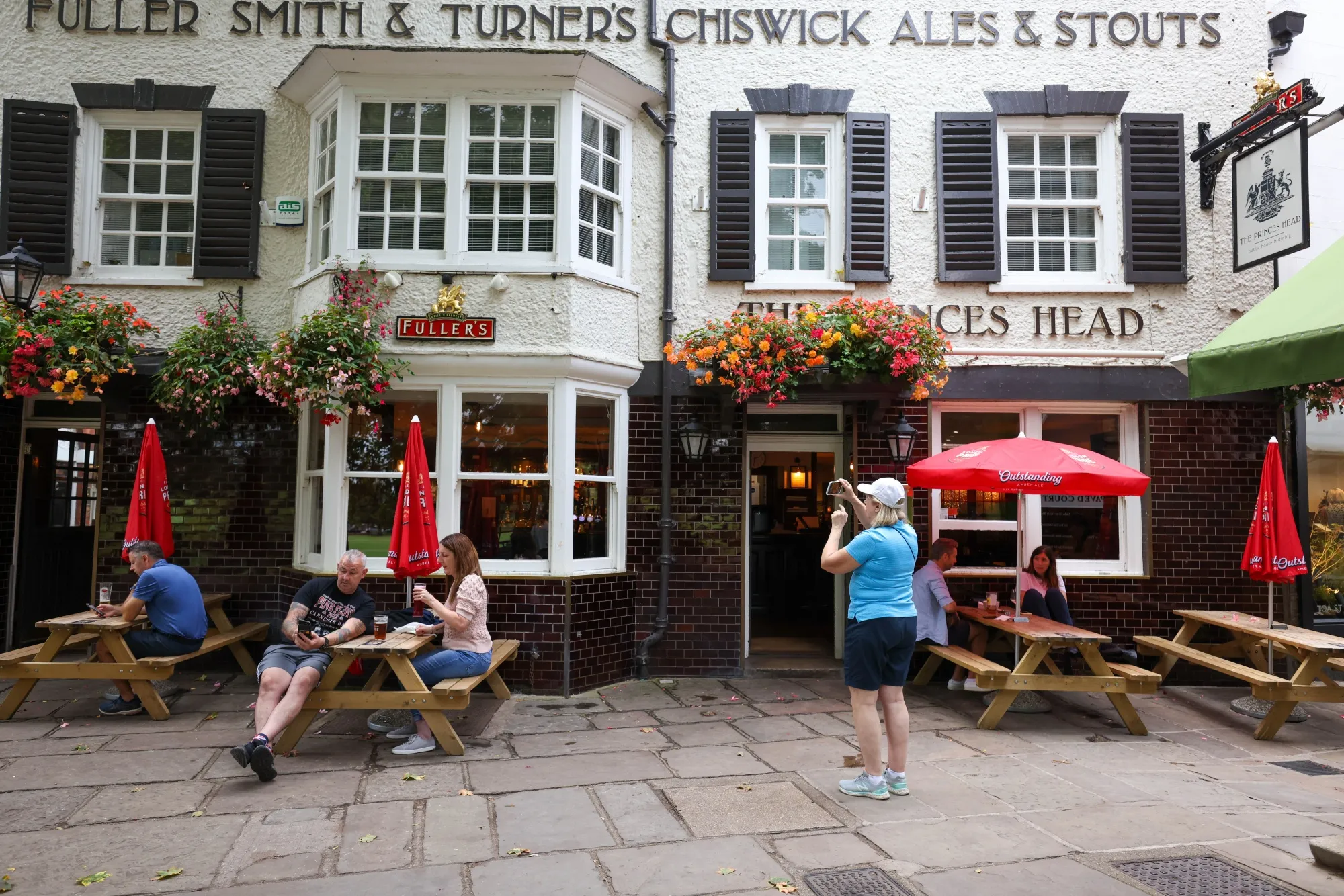 A tourist from the U.S. takes a photo outside The Prince's Head pub, the setting of the fictional Crown & Anchor pub in Apple TV's 'Ted Lasso' show, in London.