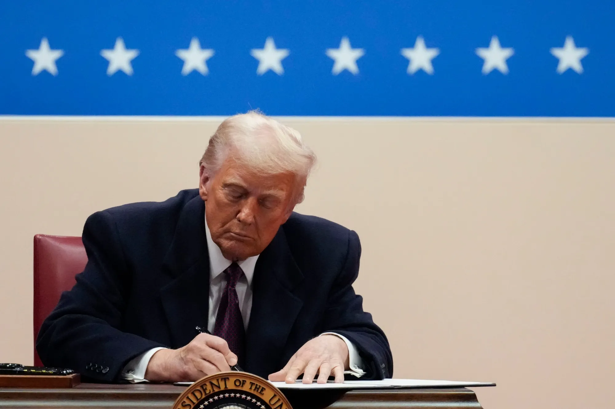 Donald Trump signs an executive order during the 60th presidential inauguration parade at Capital One Arena in Washington, DC, on Jan. 20.