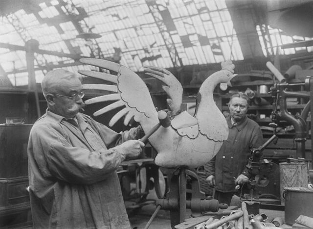 Workers are seen observing a cockerel statue they are designing