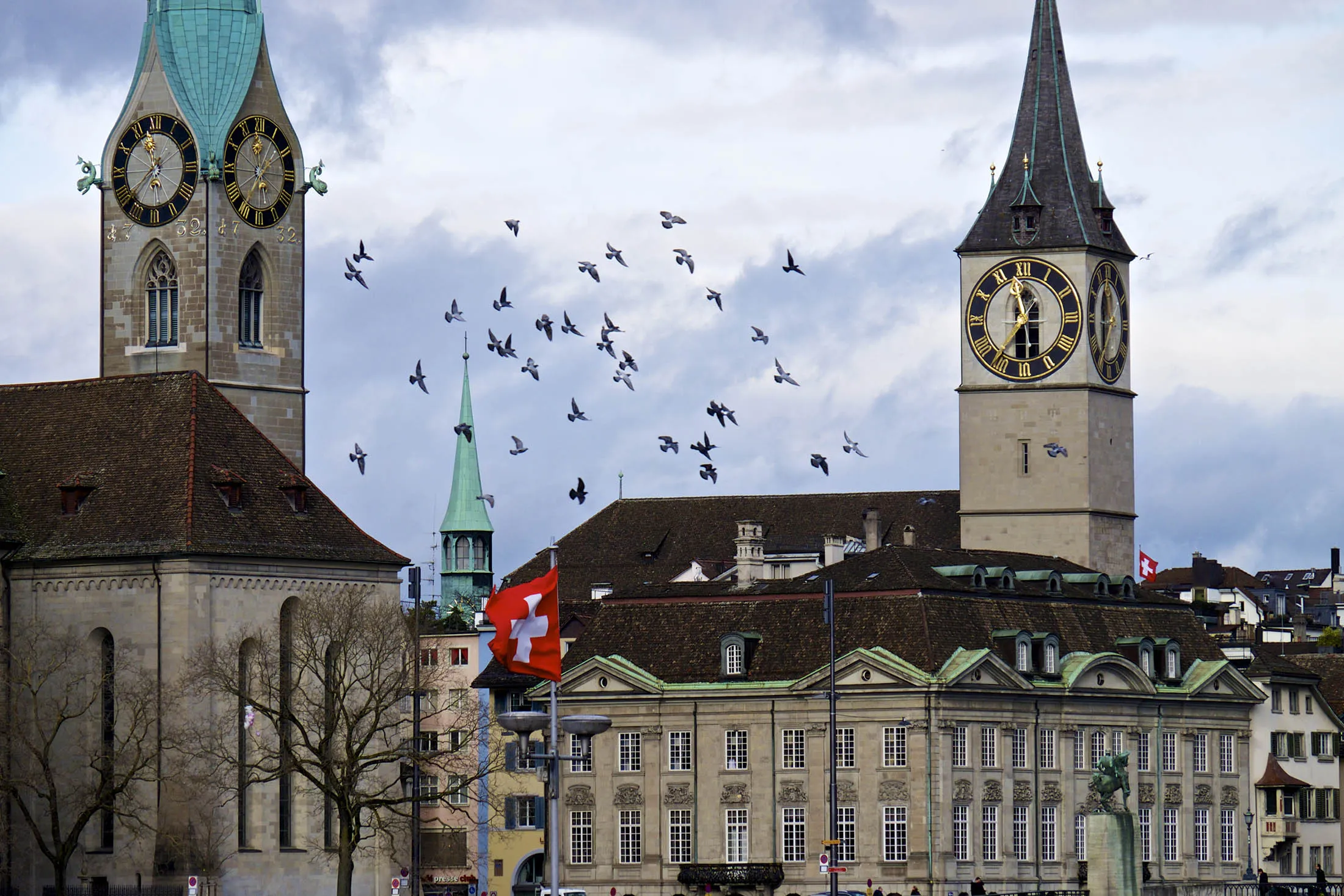 A Swiss national flag flies between the spires of Fraumeunster church, left, and St Peter's Church, right, in Zurich, Switzerland, on Thursday, Dec. 11, 2014
