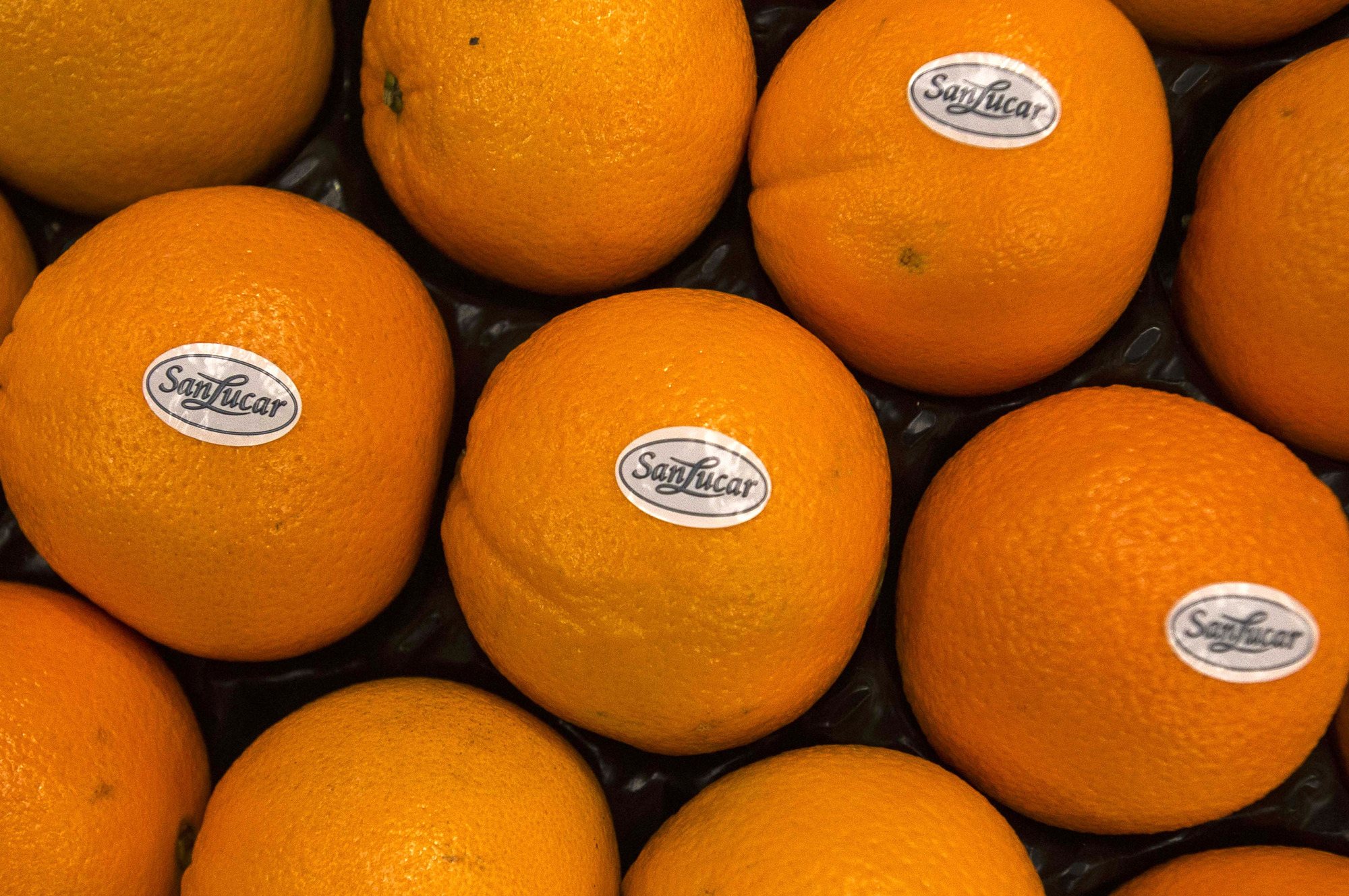Oranges sit in shipping trays after labeling with SanLucar brand stickers at the packing plant operated by Antonio Llusar y Cia, S.A. in Chilches, Spain, on Monday, Feb. 6, 2017. Spain's citrus output is seen up 20% on good weather.
