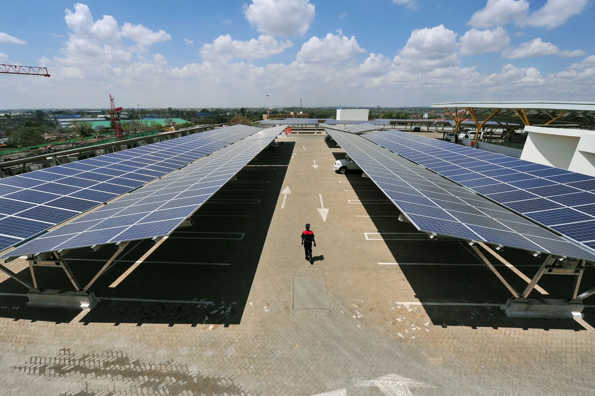 A man walks past solar panels at a solar carport.&nbsp;