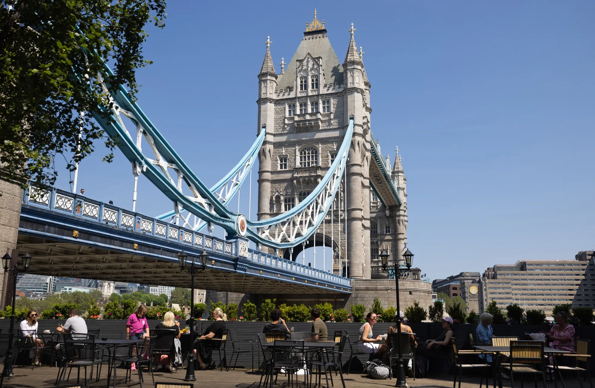 Visitors sit at restaurant in the sun near Tower Bridge in London, June 10.