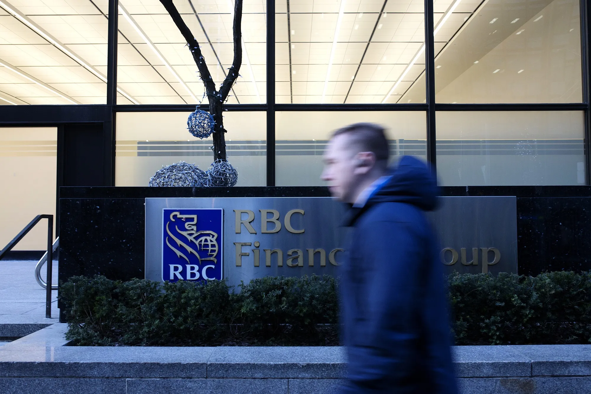 A pedestrian walks past the Royal Bank of Canada building in Toronto.
