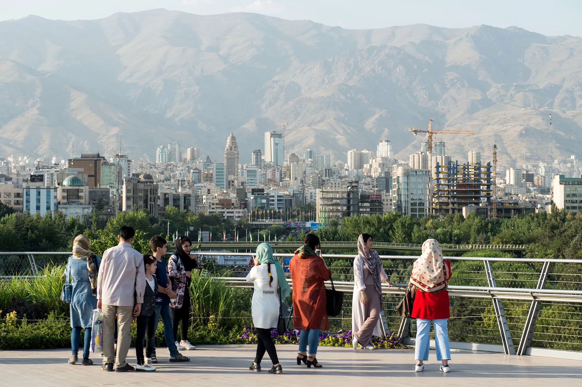 Pedestrians look out across the city skyline as they walk along the Tabiat bridge in Tehran, Iran.