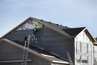 A contractor installs siding on a house under construction.