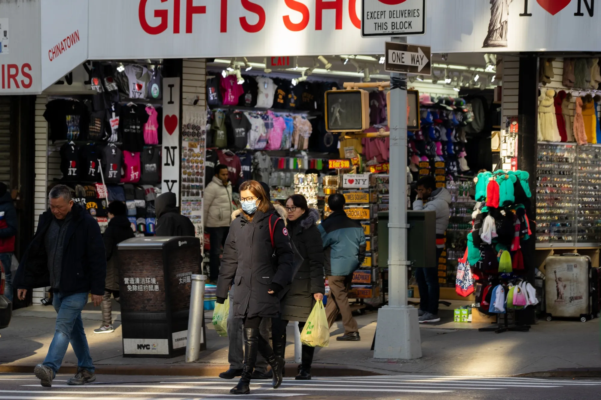 A person wears a protective mask while crossing a street in the Chinatown neighborhood of New York.