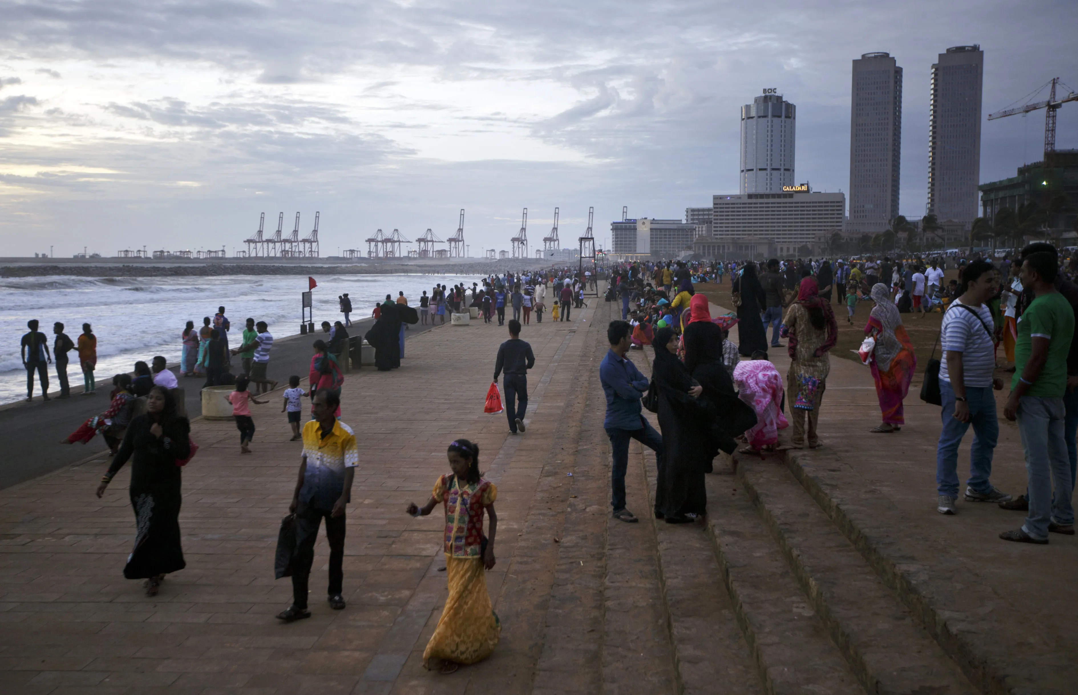 People gather on Galle Face Green as the Port of Colombo and commercial buildings in the central business district stand in the background in Colombo, Sri Lanka.
