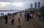 People gather on Galle Face Green as the Port of Colombo and commercial buildings in the central business district stand in the background in Colombo, Sri Lanka.
