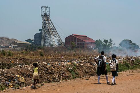 Schoolchildren walk along a dirt road past the South Ore Body Shaft at the Mopani Copper Mines Plc, the Zambian unit of Glencore Plc, in Kitwe, Zambia.