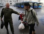 A recruitment officer directs a reservist to a bus at a mobilization center in Moscow.