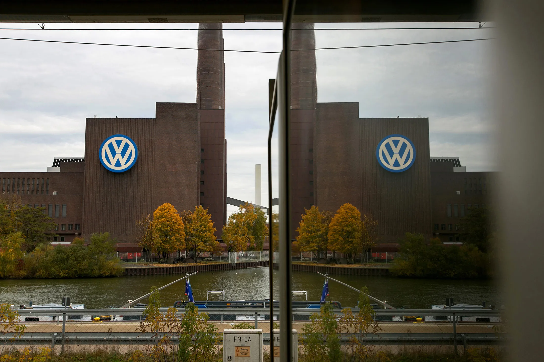 The Volkswagen AG (VW) logo sits on the automaker's headquarters in Wolfsburg, Germany, on Friday, Nov. 4, 2016. VW reached a landmark agreement with workers to cut as many as 30,000 jobs globally and save 3.7 billion euros ($3.9 billion) in expenses as the company tries to claw back from the emissions-cheating scandal and invest in electric vehicles.