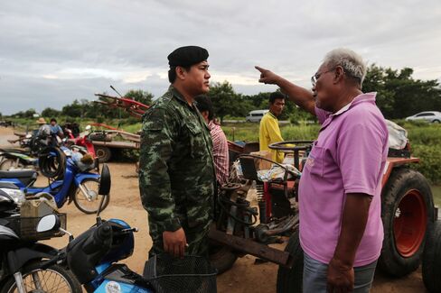 A farmer talks to a Thai Army soldier near water pumps at the Makhamtao Uthong irrigation canal in Praek Sriracha, Chainat province, on June 22, 2015. Photographer: Dario Pignatelli/Bloomberg