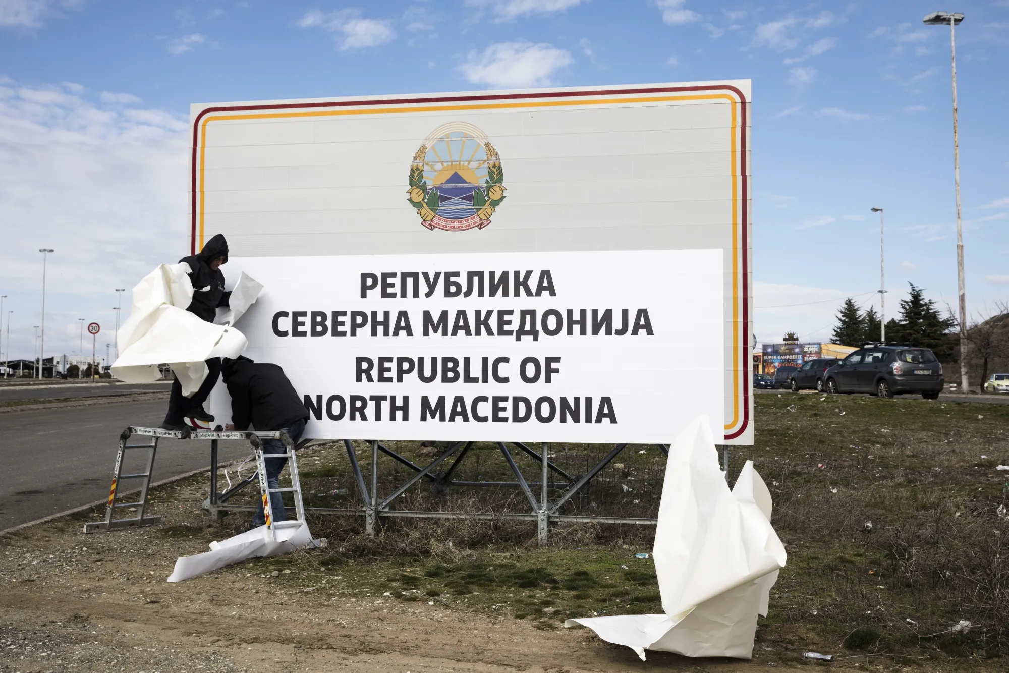 Workers cover&nbsp;"Republic of Macedonia" with a sign reading "Republic of North Macedonia" in&nbsp;2019.&nbsp;