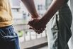 Gay couple holding hands at home