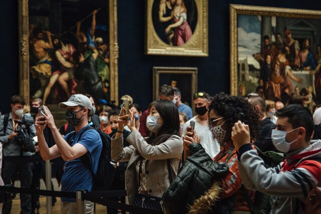 Visitors wearing protective face masks take smartphone photos of The Mona Lisa in the reopened Louvre Museum in Paris.