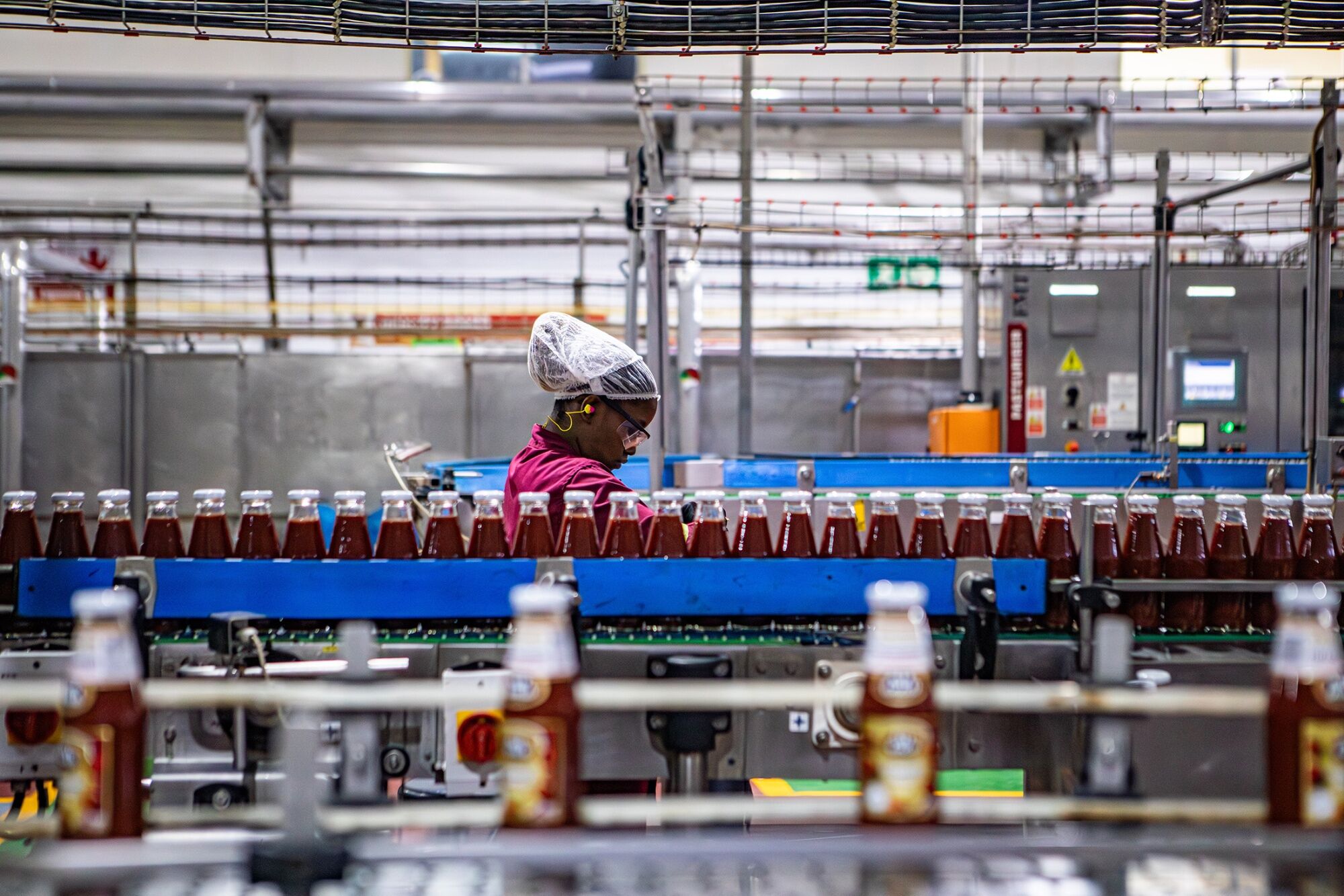 Worker overseeing bottles of tomato sauce on a production line at Tiger Brands' factory in Boksburg, near Johannesburg, South Africa.