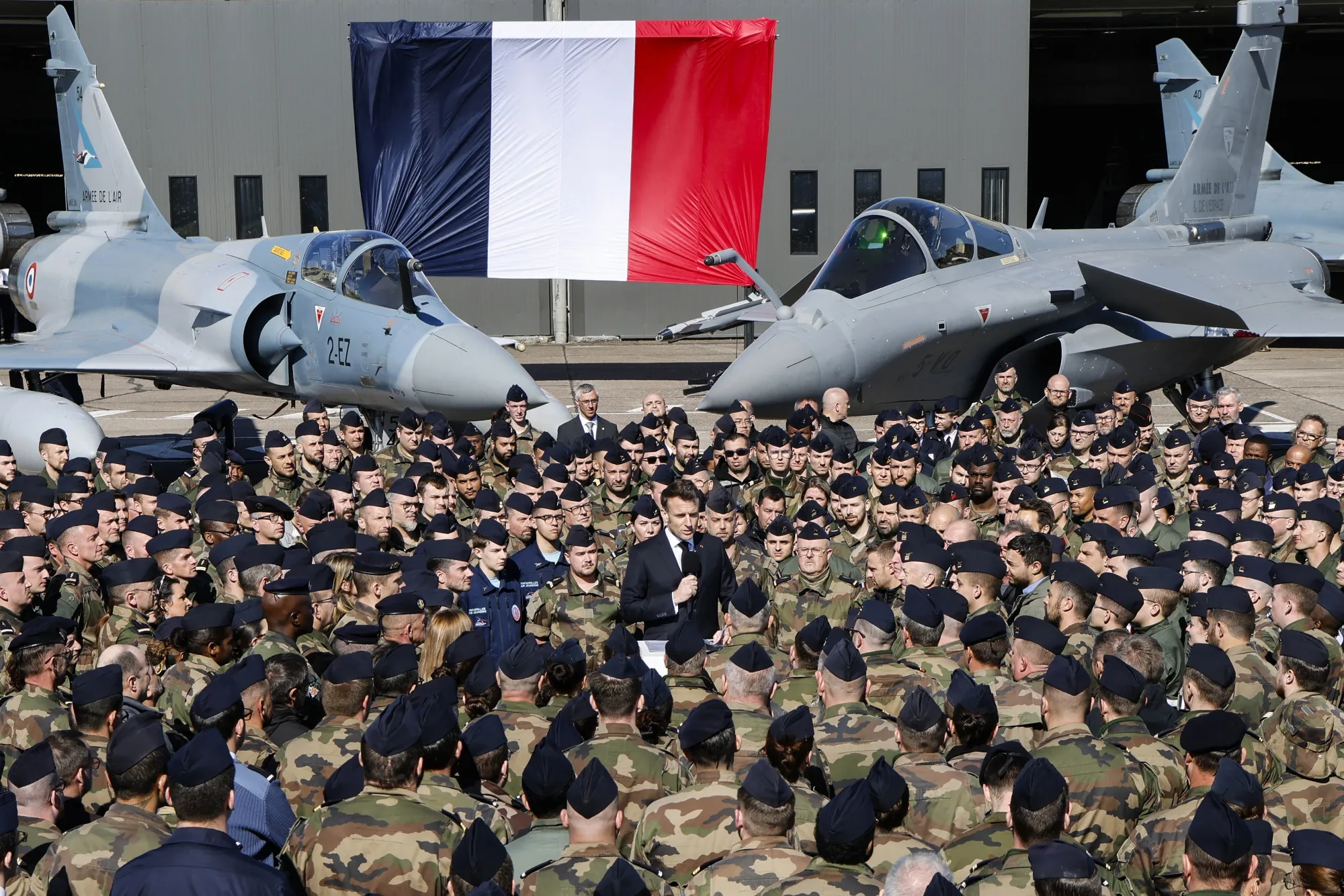 Emmanuel Macron speaks in front of Dassault Rafale, right, and Dassault Mirage 2000 fighter aircraft in Luxeuil-les-Bains, on March 18.