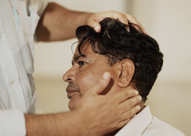 A doctor places his hand on Hemant Champanekar's neck to examine this head/neck cancer patient.
