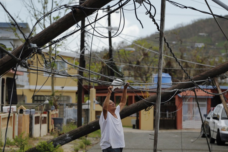A resident uses a plastic bag to move downed power cables in Puerto Rico.